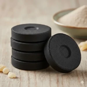 A stack of quick-light round charcoal tablets for incense on a wooden surface.
