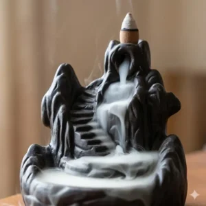 A ceramic backflow incense burner showing the smoke waterfall effect cascading down dark stone steps.