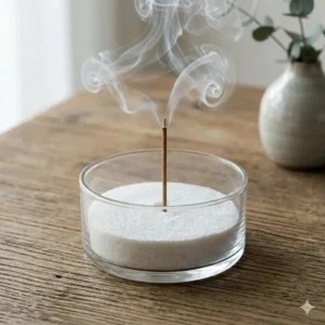 Wisps of aromatic smoke rising from a clear glass incense burner bowl during meditation.