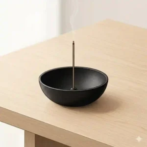 Minimalist japanese incense holder made of black cast iron on a clean wooden table.