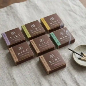 An overhead flat lay illustration of various Hibi incense matches boxes showing different aroma varieties like lavender, lemongrass, and yuzu.