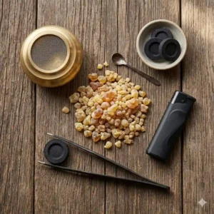 A flat lay illustration of the necessary tools for how to burn frankincense resin, including resin tears, charcoal, tongs, and a burner.