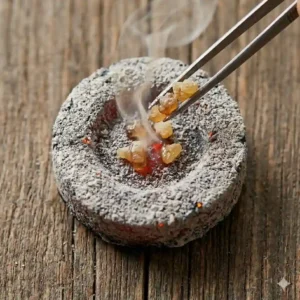 Using tongs to place a few frankincense resin tears onto a hot, prepared charcoal disc as part of how to burn frankincense resin.